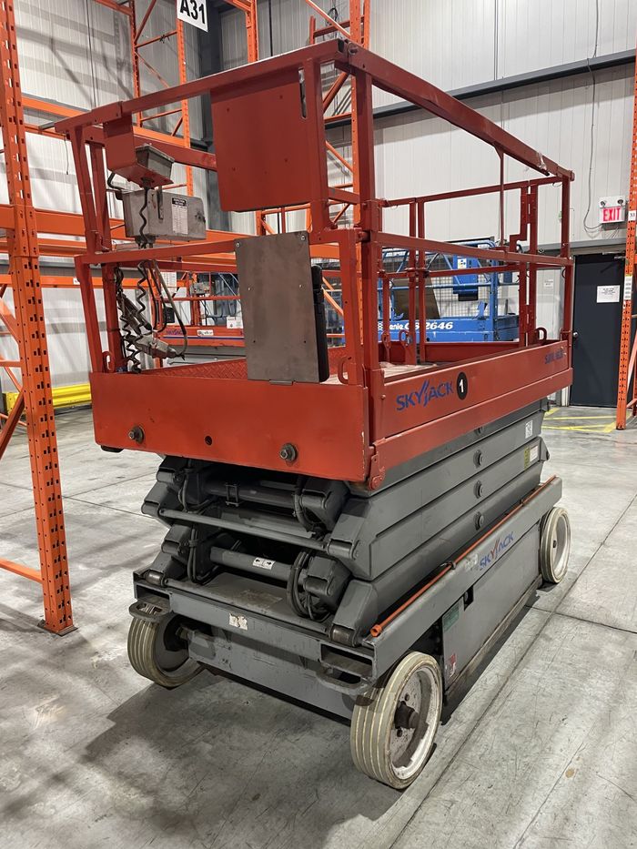 Red Skyjack 4626 scissor lift with its platform lowered, in a warehouse.